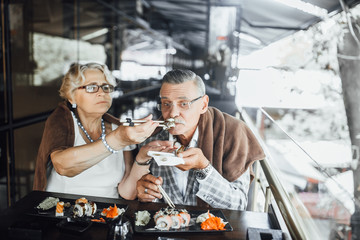 The average age of a woman holding an Asian is eating and feeding her husband by land in summer terrace