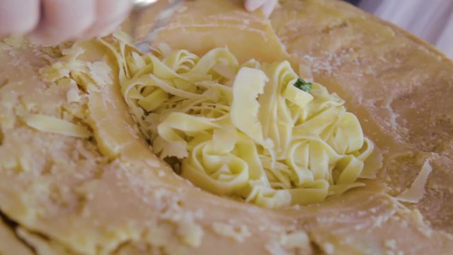 Close up view of cutting Parmesan cheese, loaf segment with rind, mature. Clipping paths, shadow separated, top view. Parmesan cheese flakes on wooden cutting board
