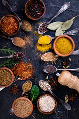 Fototapeta na wymiar Spices and herbs on black background, top view. Indian cuisine.