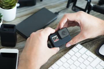 8K action camera in photographer’s hands with other accessories for photo shooting or video