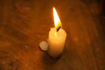 Fototapeta na wymiar Burning candle with a woody background
