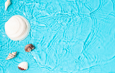 Blue water texture background on the noon sunlight with seashells. 