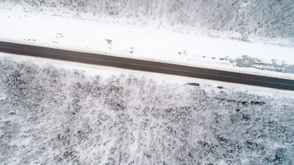 Obraz na płótnie Canvas road between forests and fields during the winter from the air