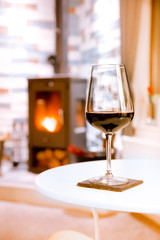 Glass of red wine on cozy fireplace background