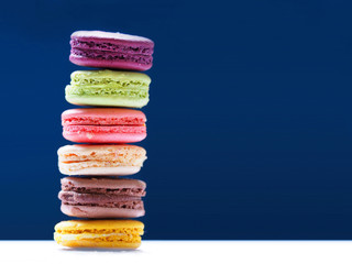 Macaron or Macaroon is sweet confection. French colorful macarons on blue background. Copy space