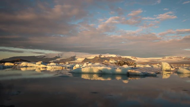 Timelapse of Glacier Lagoon / Jökulsarlón at sunrise with icebergs and clouds in view