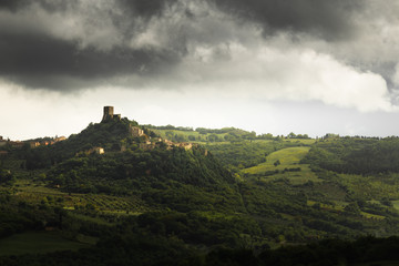 Fototapeta na wymiar Dramatic light and rainy clouds over the town Castiglione D'Orcia in Tuscany, Italy