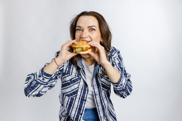 Young beautiful girl holding a Burger on a white background. Fast food, junk food, snack on the go.