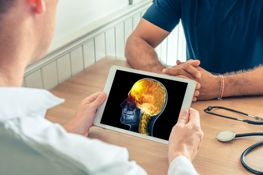 Doctor holding a digital tablet with x-ray of the head of the patient with pain on the front of the brain. Cancer headache concept