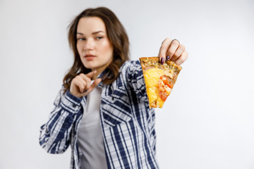 A young beautiful girl takes a piece in a plaid shirt on a white background.