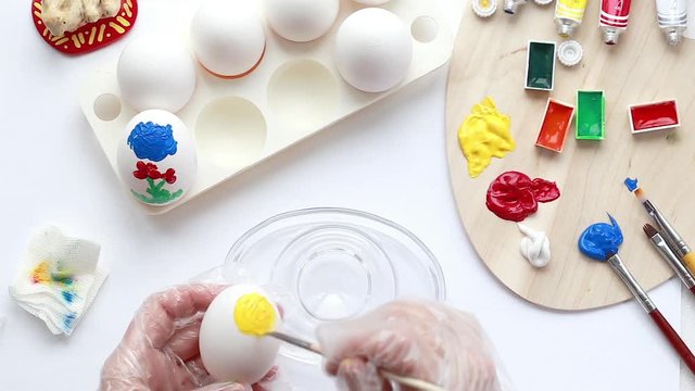 Paint eggs with colored paints with their hands. Draw a picture on the eggs for the holiday