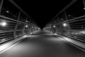 Pedestrian bridge at night in black and white.