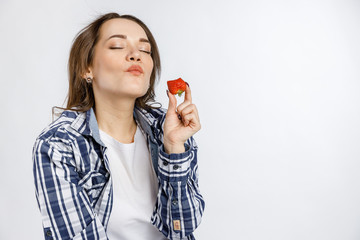 Young beautiful girl in plaid shirt holding strawberries on white background. Healthy food - vegetables, fruits and berries.