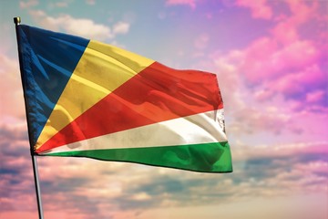 Fluttering Seychelles flag on colorful cloudy sky background. Prosperity concept.