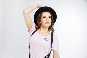 Fototapeta premium Young beautiful girl posing in stylish black hat on white background. Emotions and gestures.