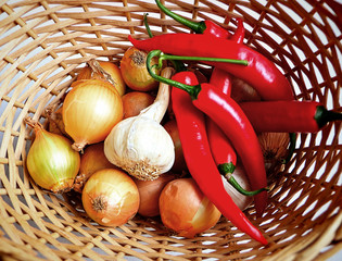 Ingredients of a healthy and spicy cuisine: onions, garlic and red peppers chili in a kitchen basket
