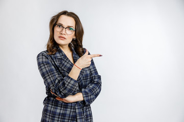 Young beautiful girl in a strict plaid suit posing on a white background. Emotions and feelings at work and office.