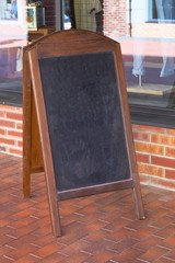 Wooden frame chalkboard standing on the sidewalk. Empty space concept for advertising, mockup.