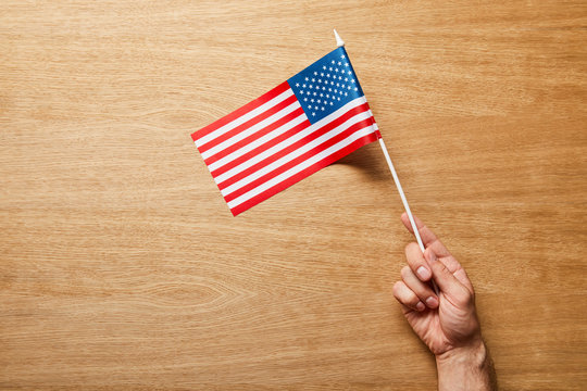 cropped view of man holding american flag on wooden background