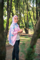 Naklejka na ściany i meble Young attractive Muslim Malay woman, modern contemporary fashion in hijab, close up portrait face and body, blurred background smiling and happy at park.
