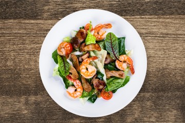Spaghetti with shrimps, tomatoes and chopped parsley on wooden desk