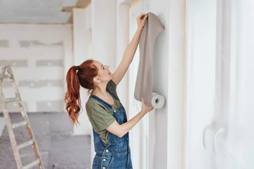 Foto op Plexiglas Young woman trying out new wallpaper at home © contrastwerkstatt