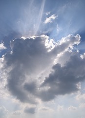Fototapeta na wymiar Sun shining through clouds blue sky