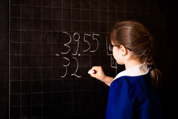 Italian elementary school girl trying to solve a mathematics examples, making a long division at...