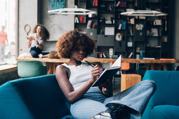 two young multiracial women writing and working in modern open space