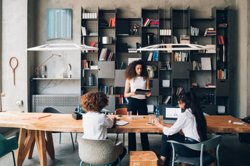 three young multicultural students discussing project in coworking office with teacher