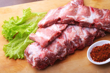 Raw Ribs on a rustic cutting board with salt, pepper and grinder for spices . copy space. Top View.