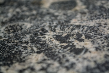 Background or texture from a gray stone with round spots and stains. Natural material. Glossy surface.