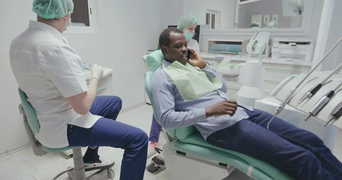 black patient talk on phone in dental chair