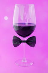 cup of wine in a pink background with a bow tie