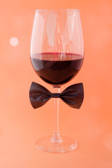 cup of wine in a coral background with a bow tie