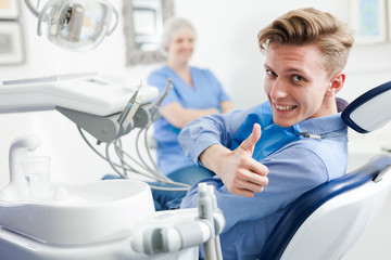 Male is sitting satisfied in chair after treatment in dental office