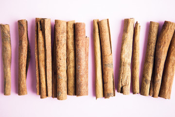 Set of cinnamon sticks on pink background