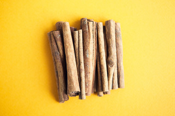 Set of cinnamon sticks on yellow background