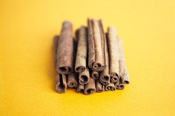 Set of cinnamon sticks on yellow background