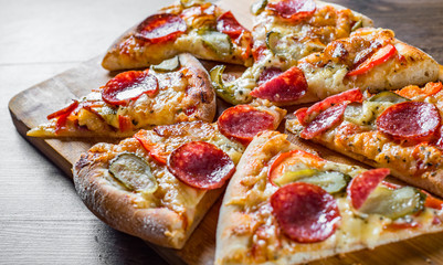 Pepperoni Pizza with Mozzarella cheese, salami, bacon, Tomato sauce, pepper, Spices and pickled cucumbers. Italian pizza on wooden table background