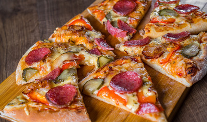 Pepperoni Pizza with Mozzarella cheese, salami, bacon, Tomato sauce, pepper, Spices and pickled cucumbers. Italian pizza on wooden table background