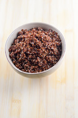 Cooked prep red quinoa in a bowl on a wooden background. Top view.