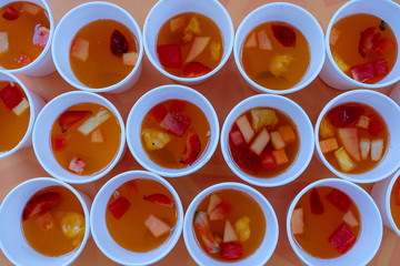 Lots of sweet fruit lemonade from red strawberries, melons and pineapple in a in white cups . Close up. Refreshing drink from pieces of fruit