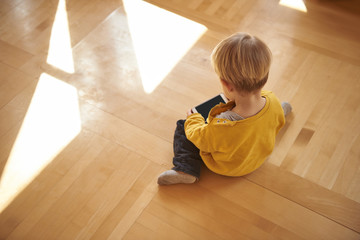 Cute little boy sitting on the floor and using cellphone