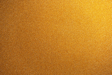 Abstract gold glitter paper texture background or backdrop. Empty shimmer paper or yellow shiny paperboard for design element. Shimmering surface for christmas holiday or new year celebration concepts