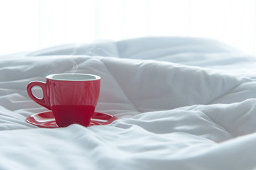 Fresh morning red cup coffee on the white bed. Lifestyle Concept