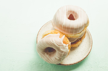 Donats in white glaze. Fresh pastries. A plate from donats in white glaze. Closeup. Sweet food concept.