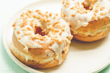 Donat. A plate from donata in white glaze with nuts. Closeup. Fresh pastries. Sweet food concept.