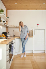 Charming young woman standing in kitchen at home