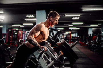 Fototapeta na wymiar Strong Bodybuilder Doing Heavy Weight Exercise For Back On Machine. T-pull exercise.